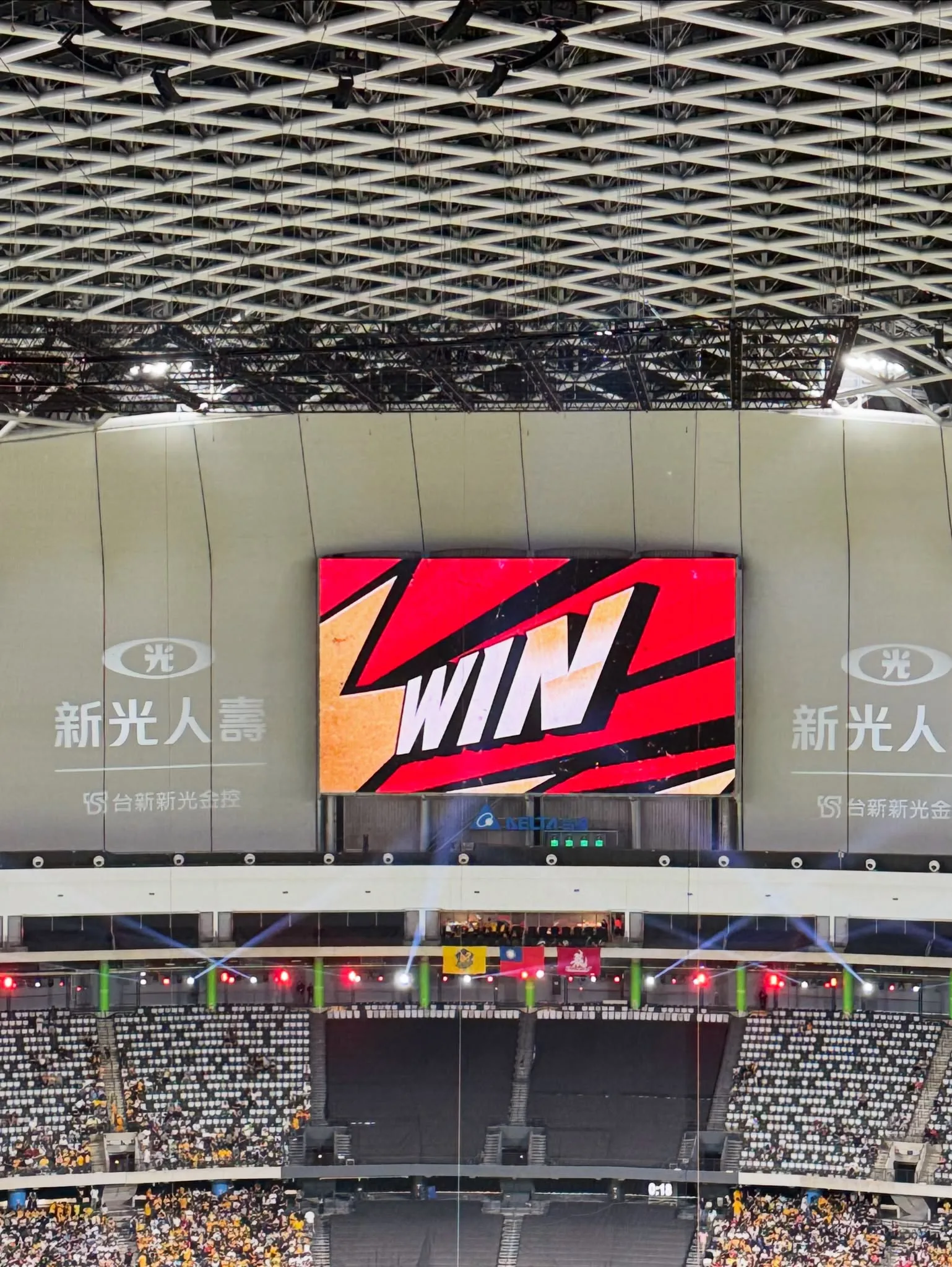 台北大巨蛋記分板顯示 WIN 字樣，球場燈光與觀眾席在下方